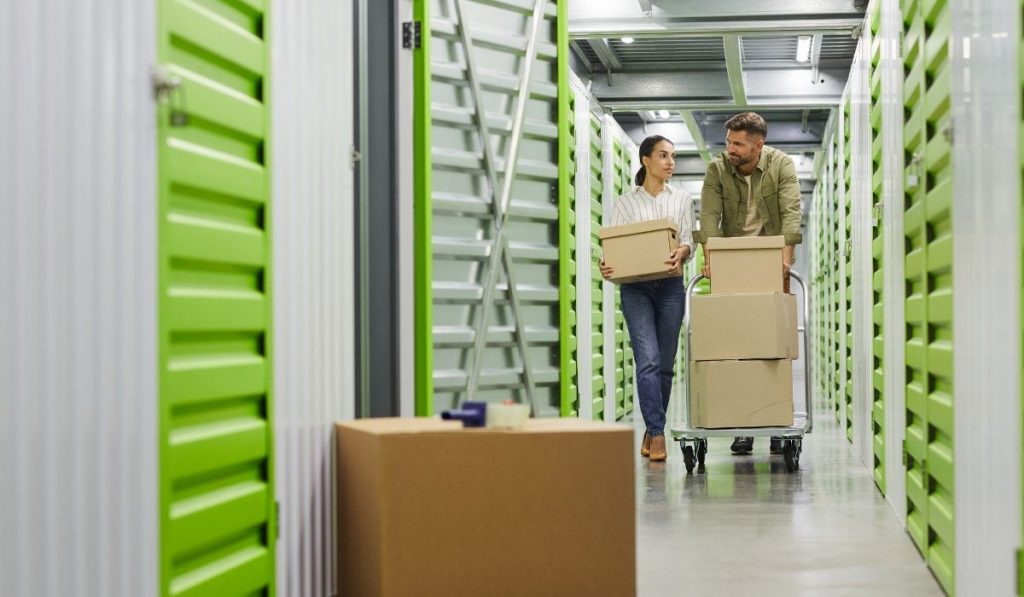 couple in a storage facility bringing some boxes of different stuff to store