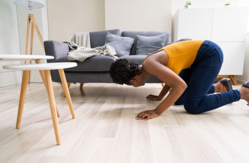 girl looking for something under the sofa