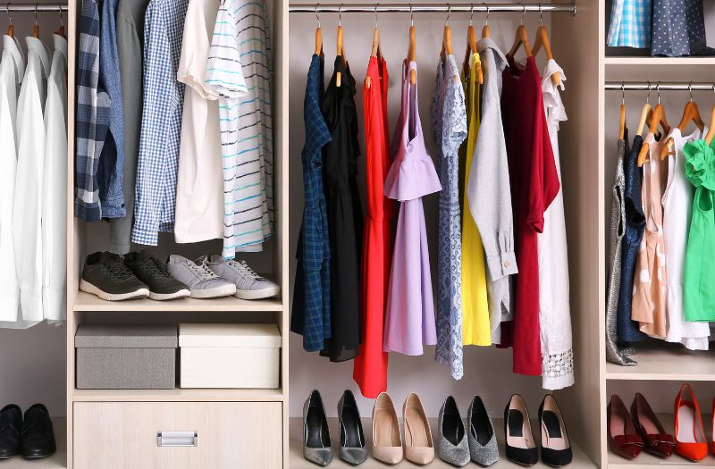 open concept closet with clothes hanging and shoes align at the bottom