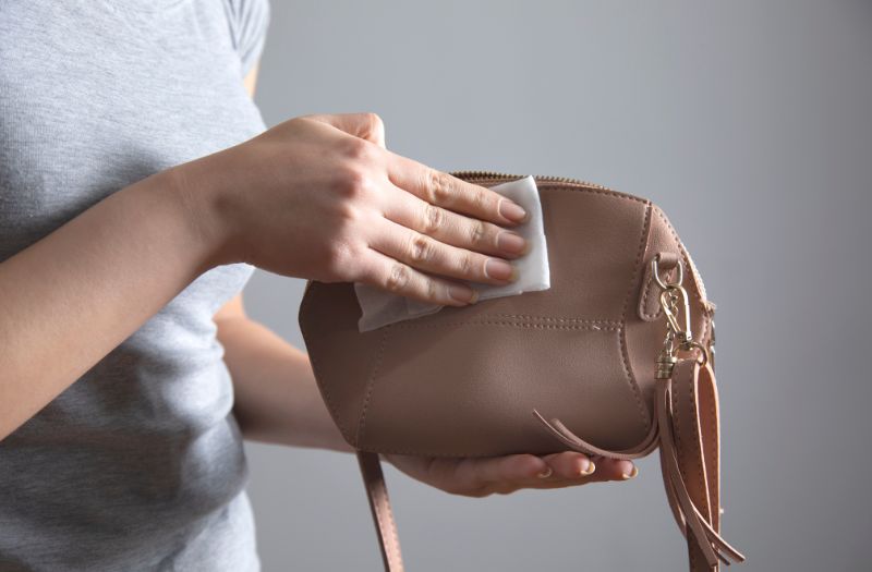 woman cleaning a small brown purse