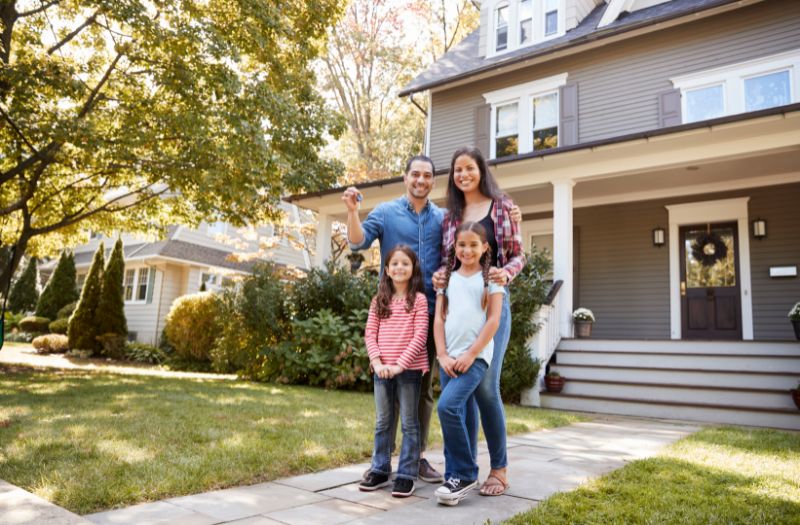 happy family picture in front of their new house