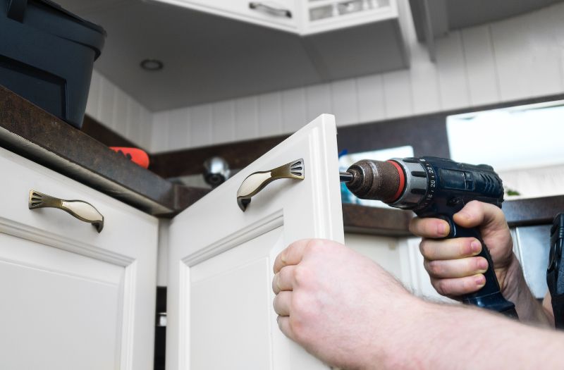 man installing a hook on a cabinet door