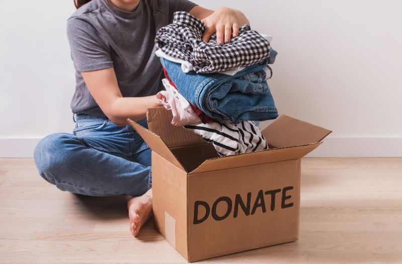 woman putting used clothes in a donate box